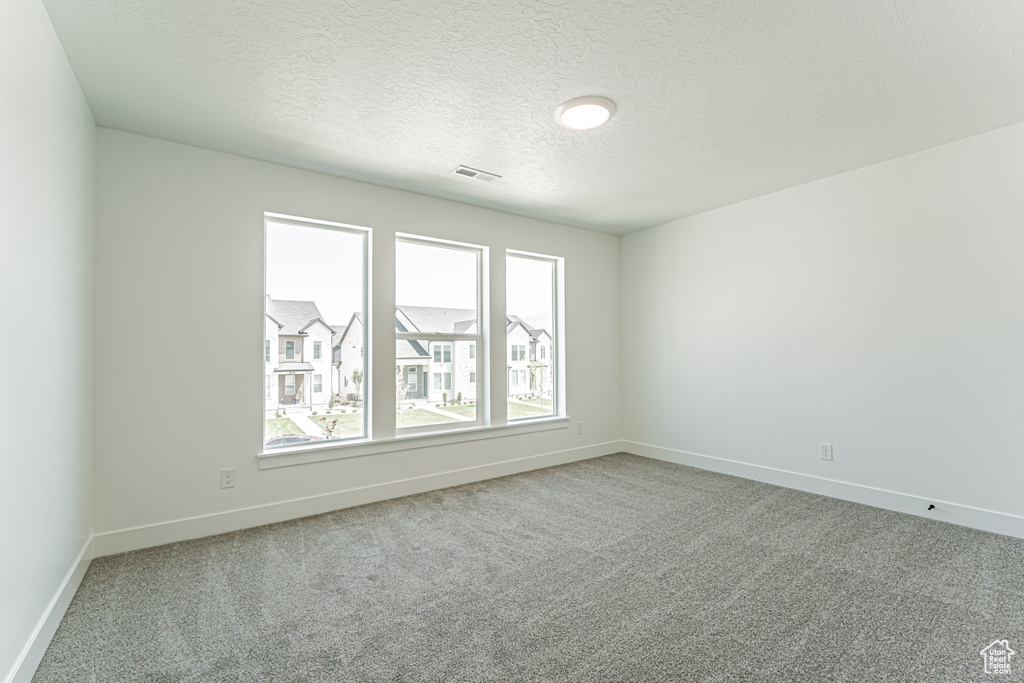 Carpeted empty room featuring baseboards and a textured ceiling