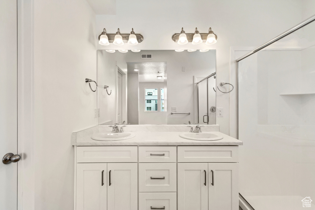 Bathroom with a shower stall, visible vents, a sink, and double vanity
