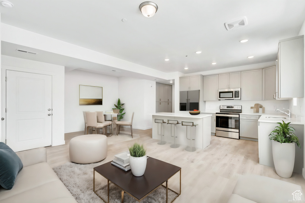 Living area with light wood-style flooring, visible vents, and recessed lighting