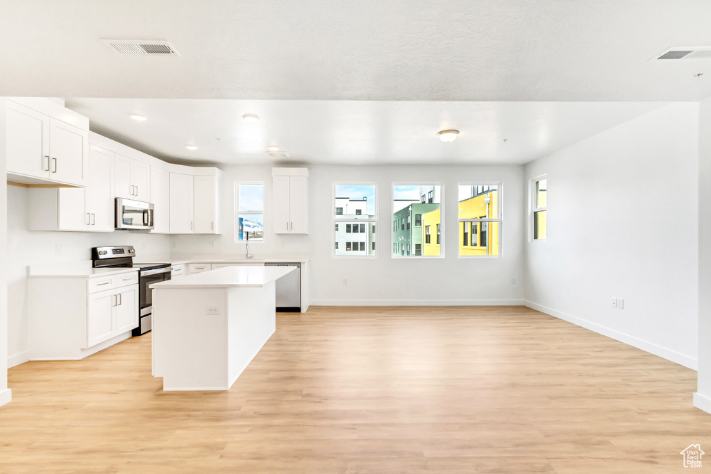 Kitchen featuring visible vents, stainless steel appliances, a center island, and baseboards