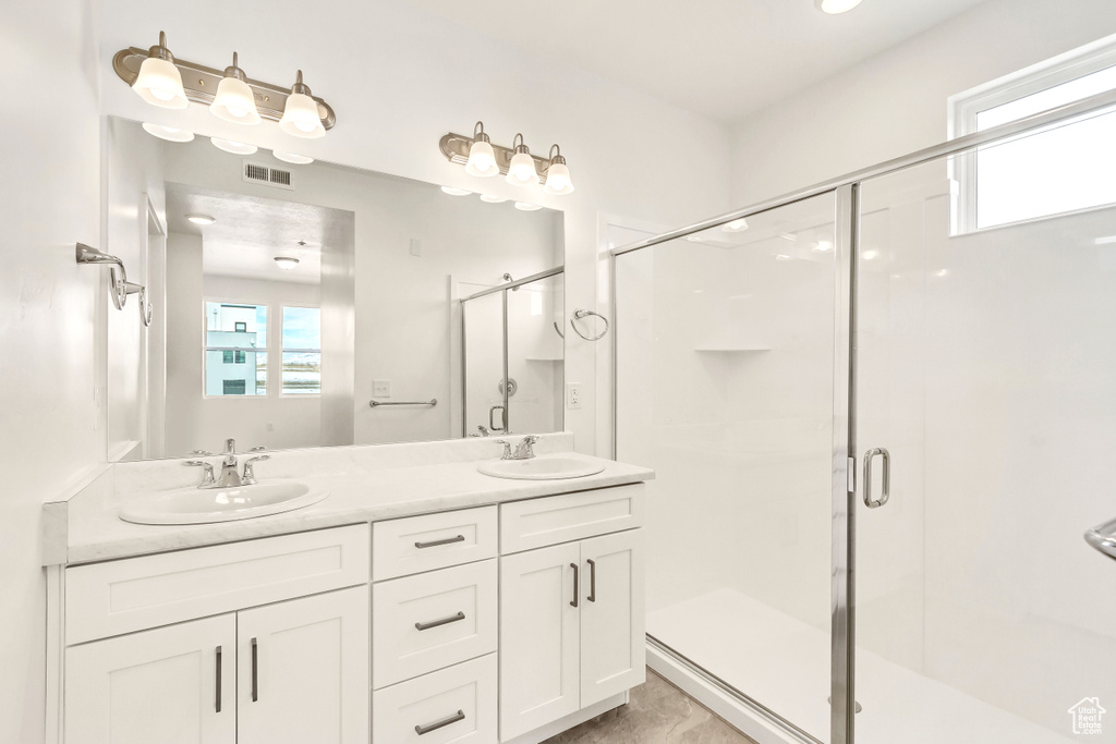 Bathroom with visible vents, a stall shower, and a sink