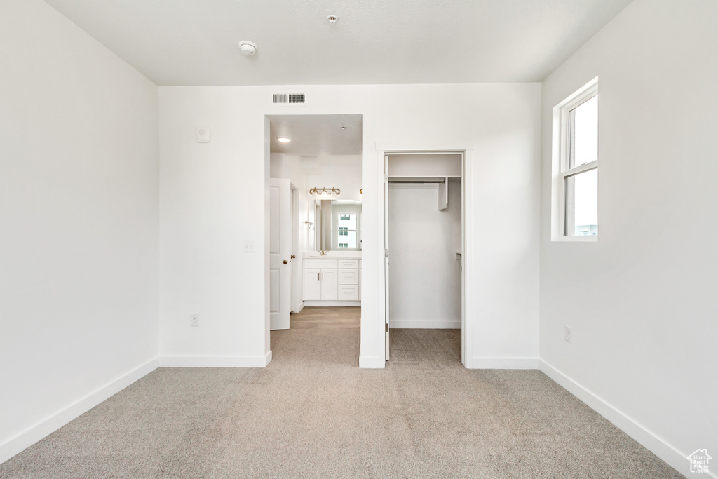 Unfurnished bedroom featuring a spacious closet, visible vents, carpet floors, a closet, and baseboards
