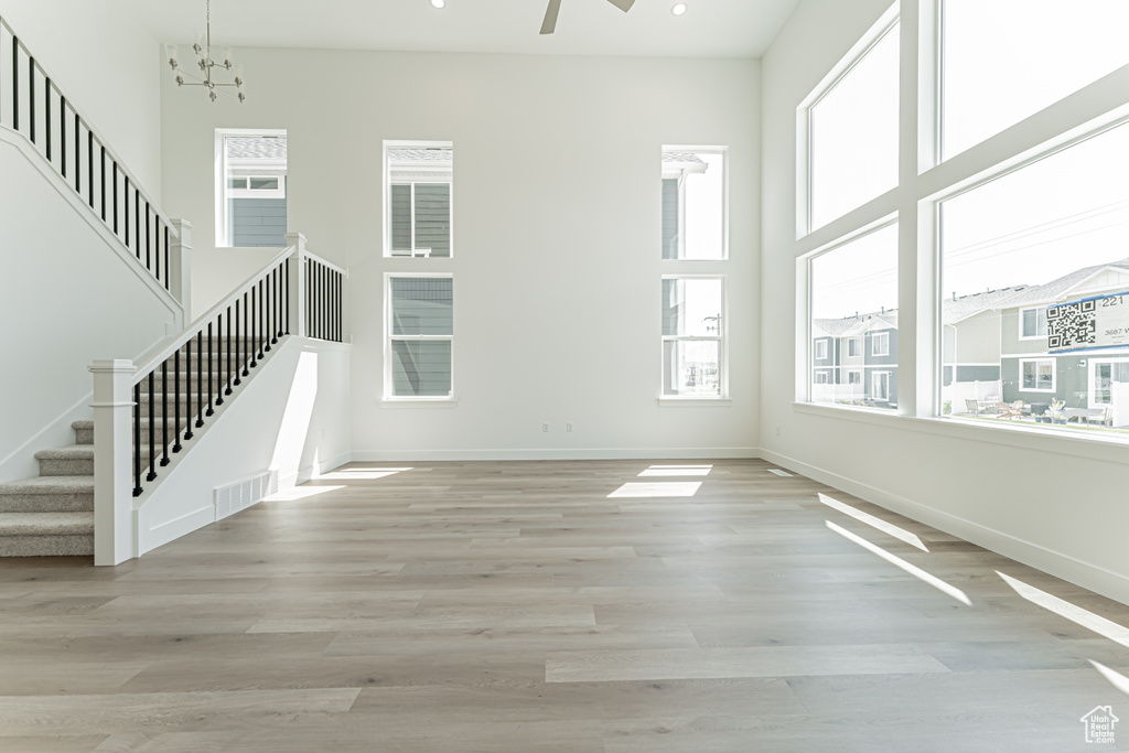 Unfurnished living room with stairway, light wood finished floors, a chandelier, and recessed lighting