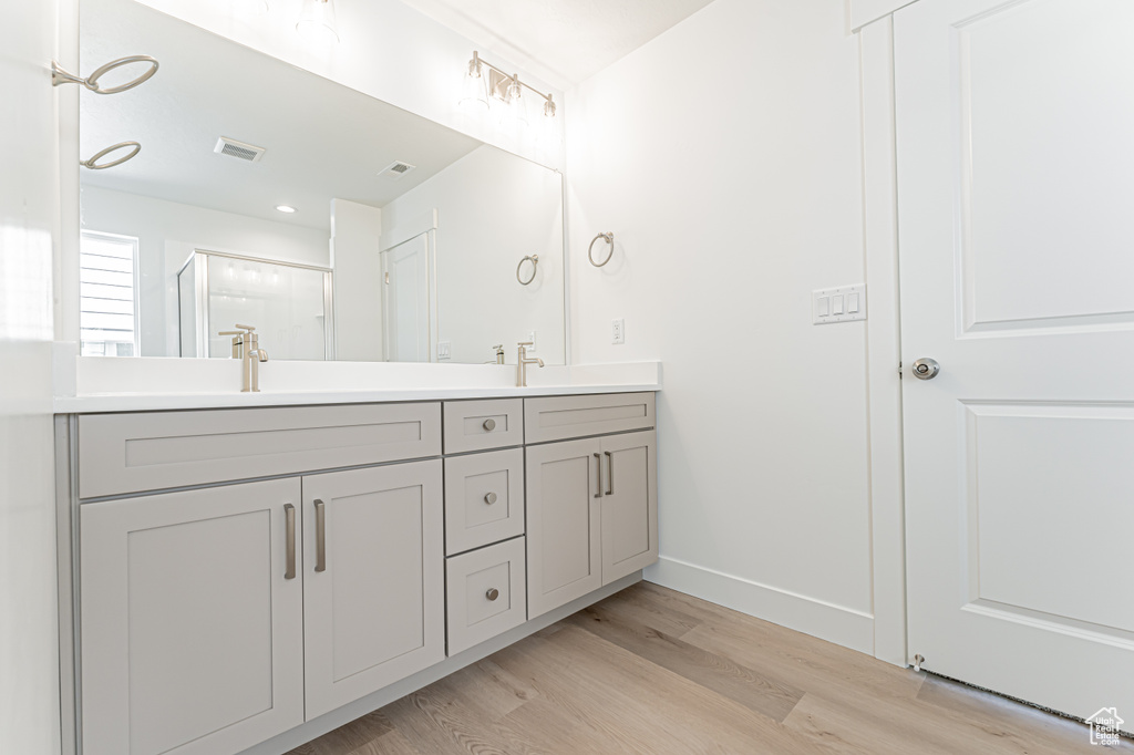 Full bathroom with double vanity, wood finished floors, and a shower stall