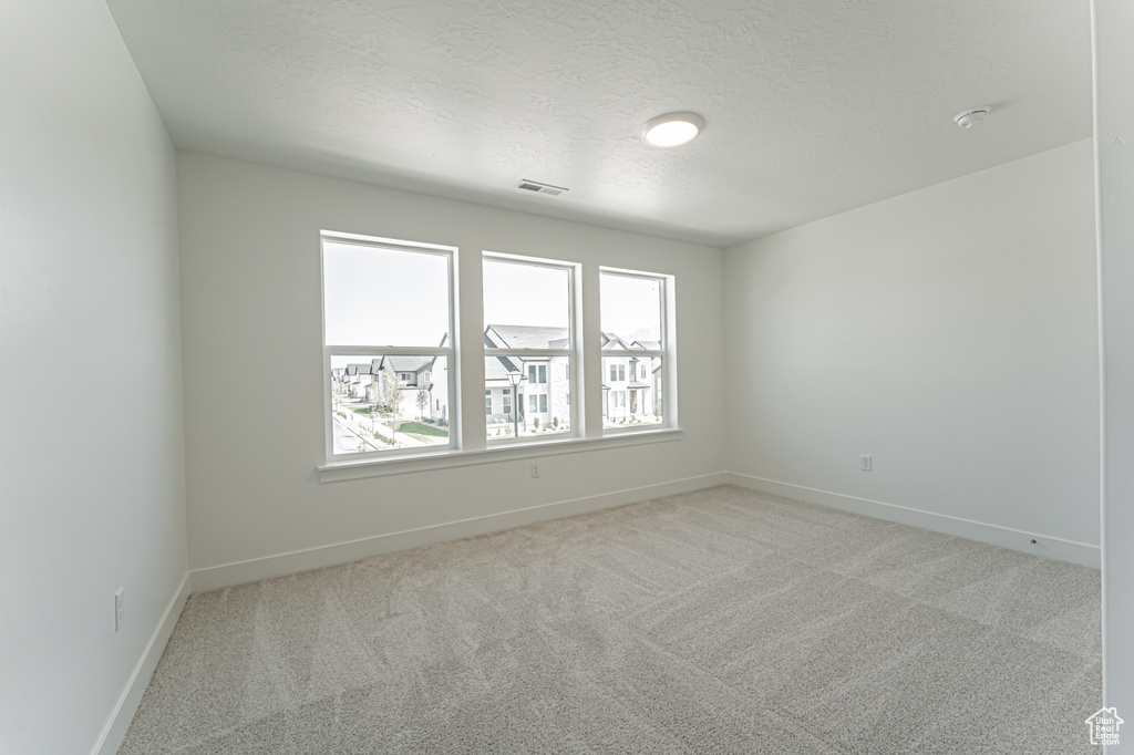 Spare room with light carpet and a textured ceiling