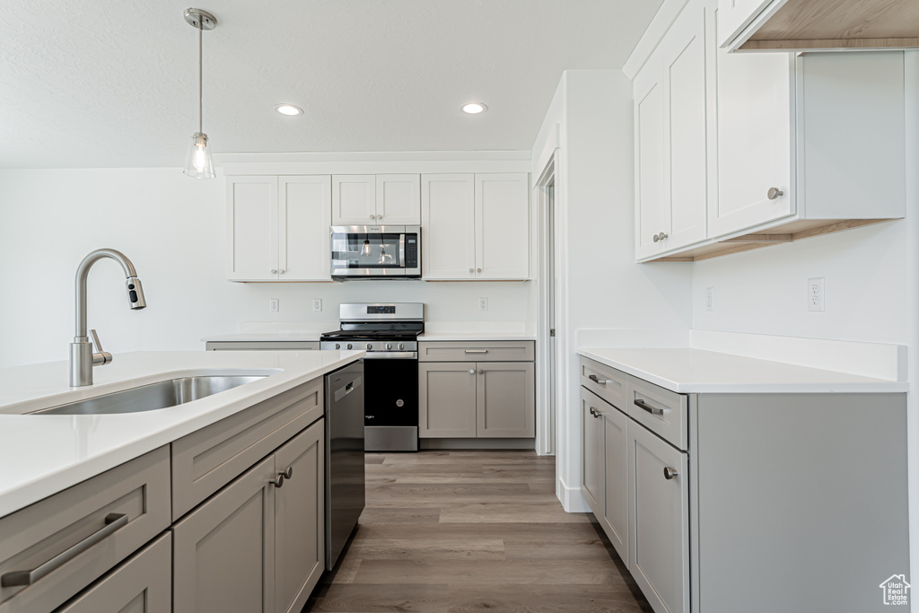 Kitchen with appliances with stainless steel finishes, gray cabinetry, recessed lighting, light countertops, and light wood finished floors