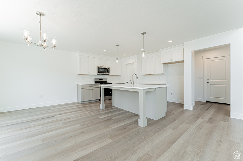 Kitchen with stainless steel appliances, recessed lighting, light countertops, light wood-type flooring, and a chandelier