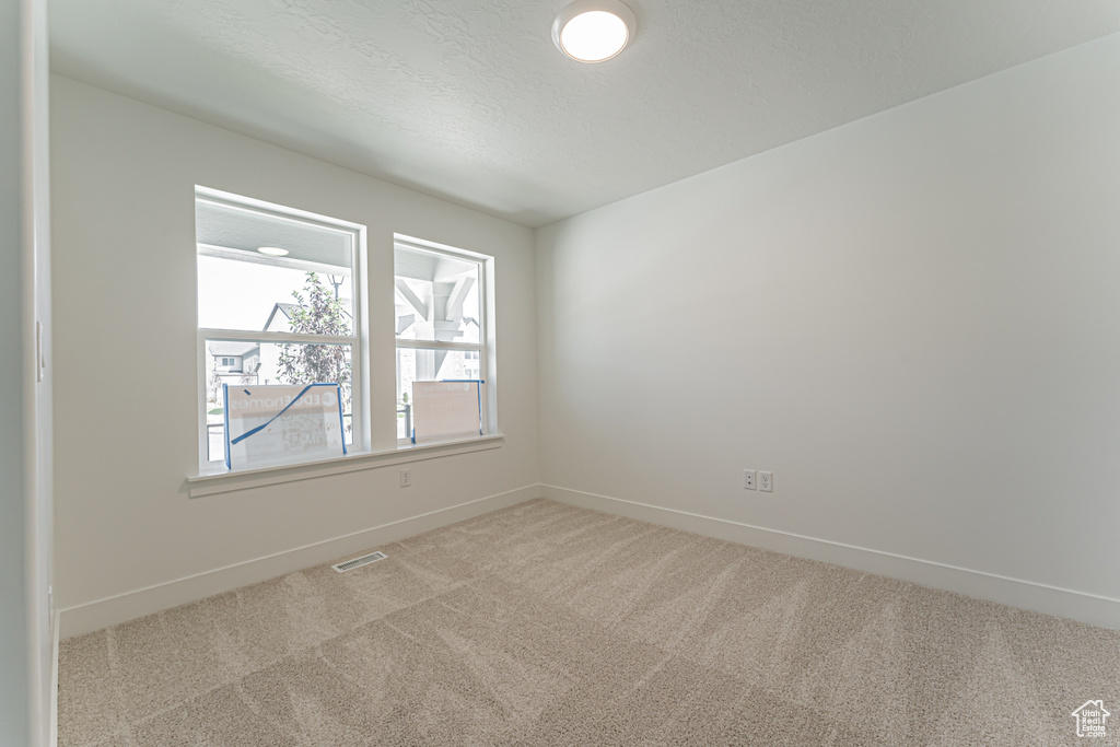 Carpeted empty room with baseboards and a textured ceiling