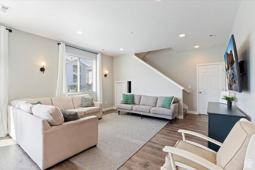 Living room featuring recessed lighting, stairway, wood finished floors, visible vents, and baseboards