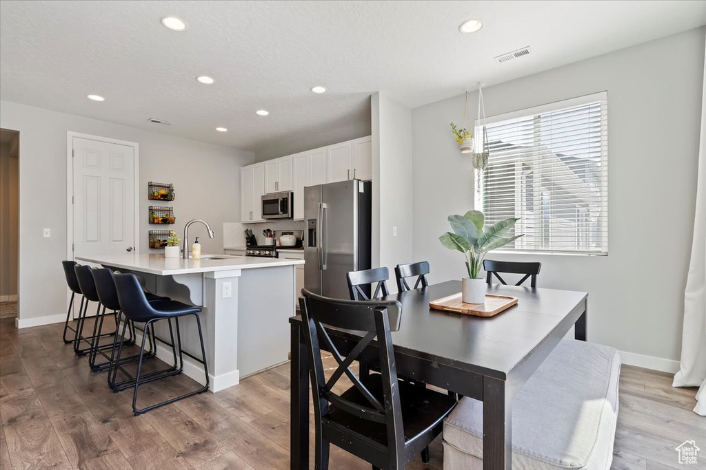 Dining area with baseboards, light wood finished floors, visible vents, and recessed lighting
