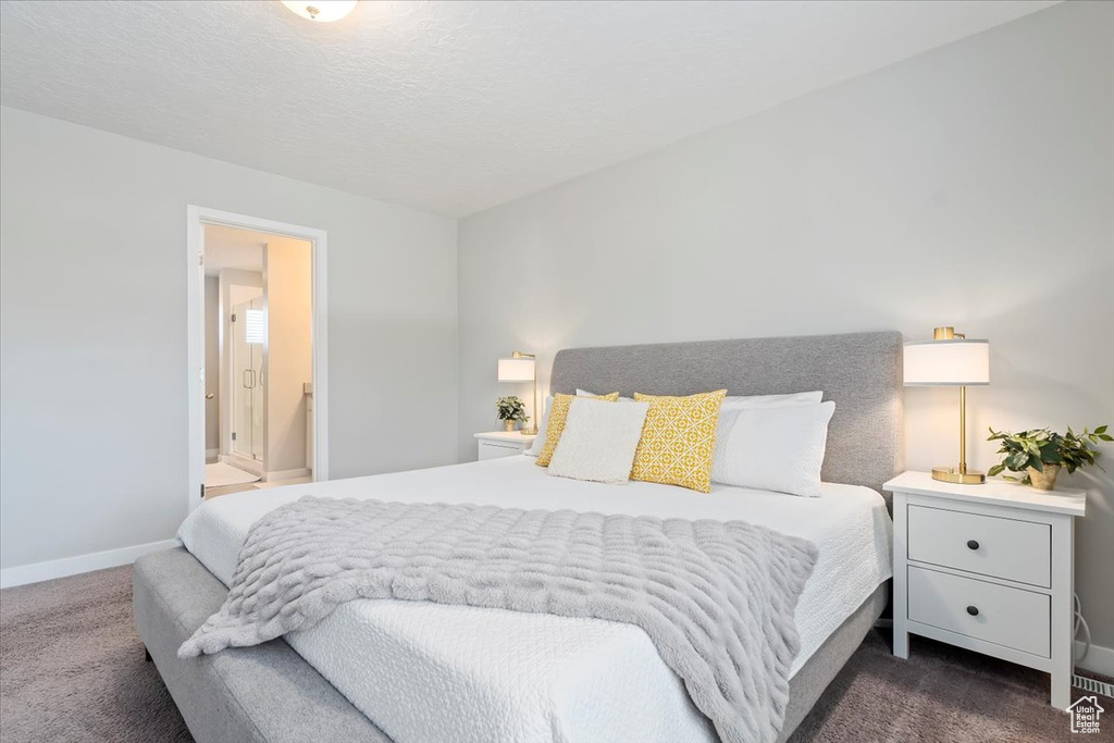Bedroom with dark carpet, ensuite bath, and baseboards