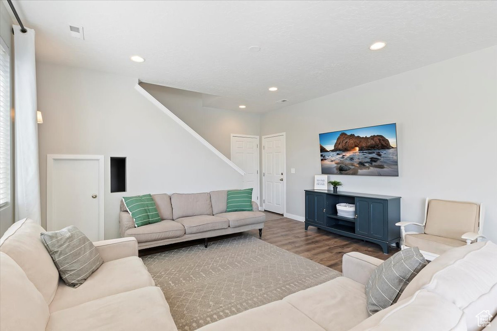 Living room featuring stairs, wood finished floors, baseboards, visible vents, and recessed lighting