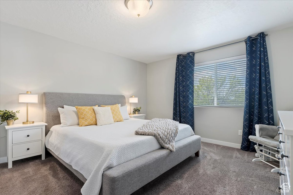 Bedroom featuring baseboards and dark carpet