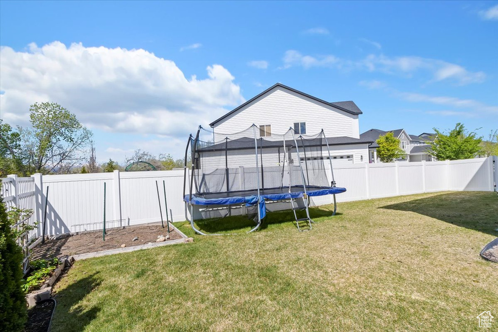View of yard with a trampoline and a fenced backyard