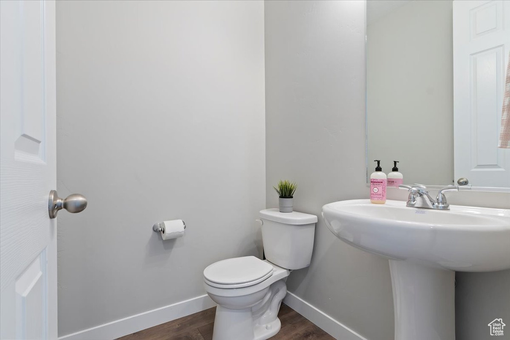 Bathroom featuring wood finished floors, toilet, baseboards, and a sink