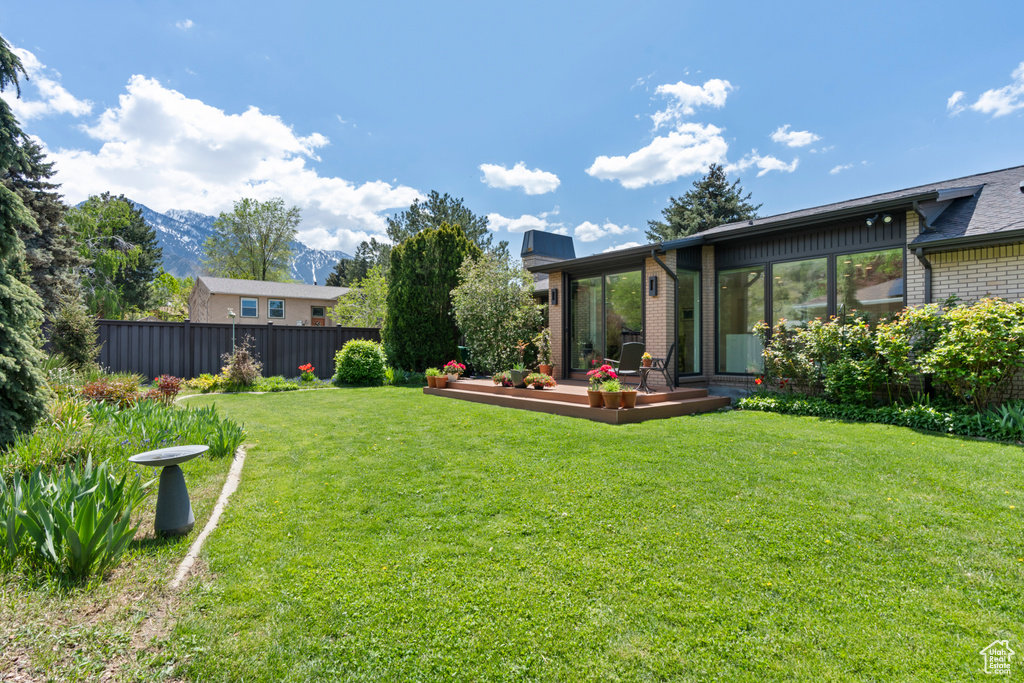 View of yard featuring fence and a deck with mountain view