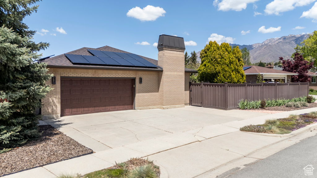 Single story home with a mountain view, an attached garage, solar panels, and brick siding