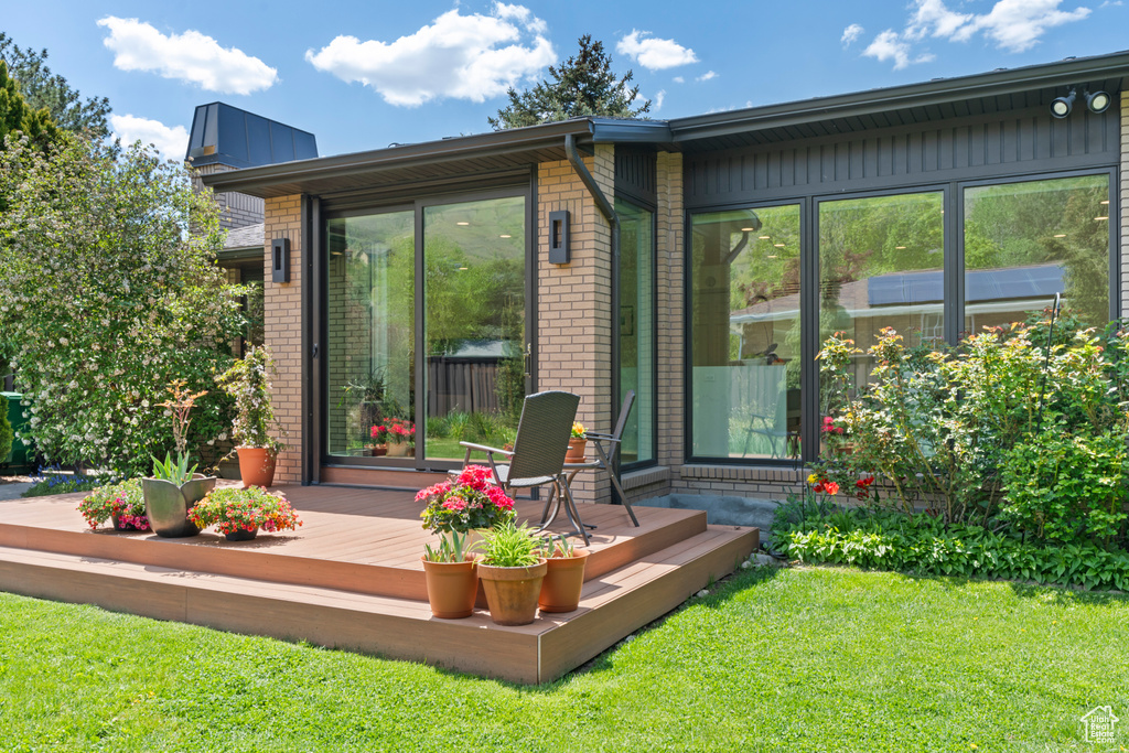 Rear view of property featuring a yard, brick siding, and a deck