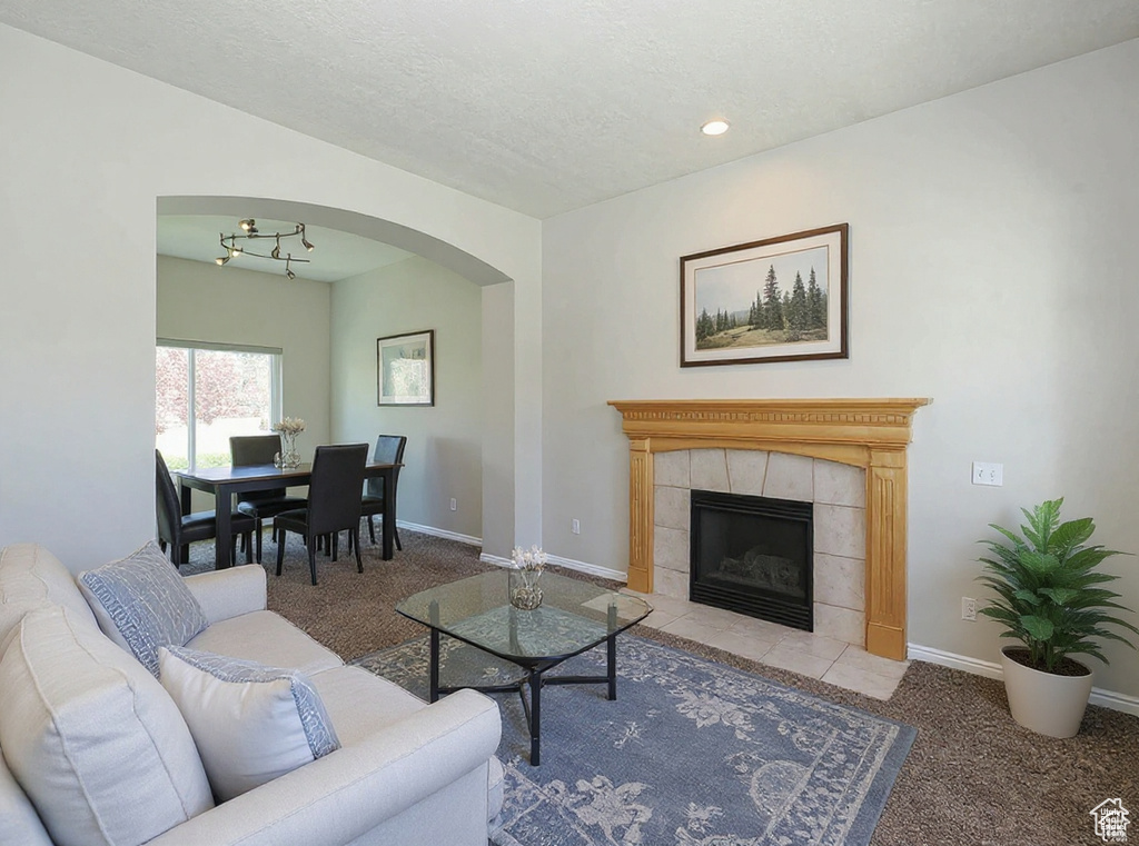 Carpeted living room featuring arched walkways, a tile fireplace, and recessed lighting