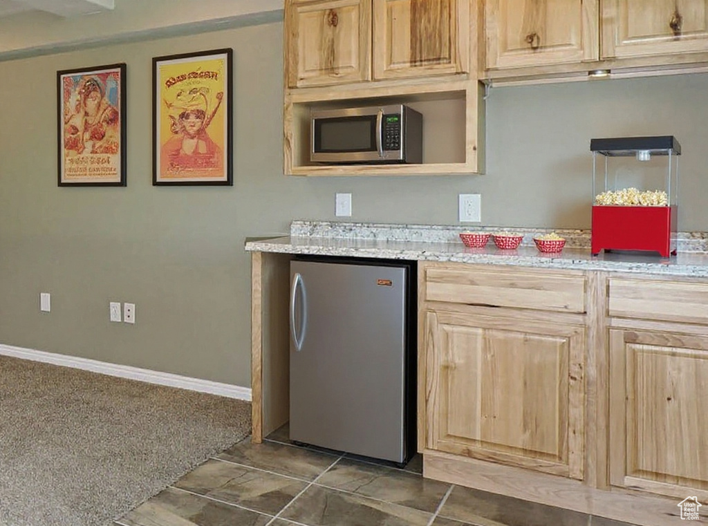 Kitchen featuring appliances with stainless steel finishes, light brown cabinets, and light stone counters