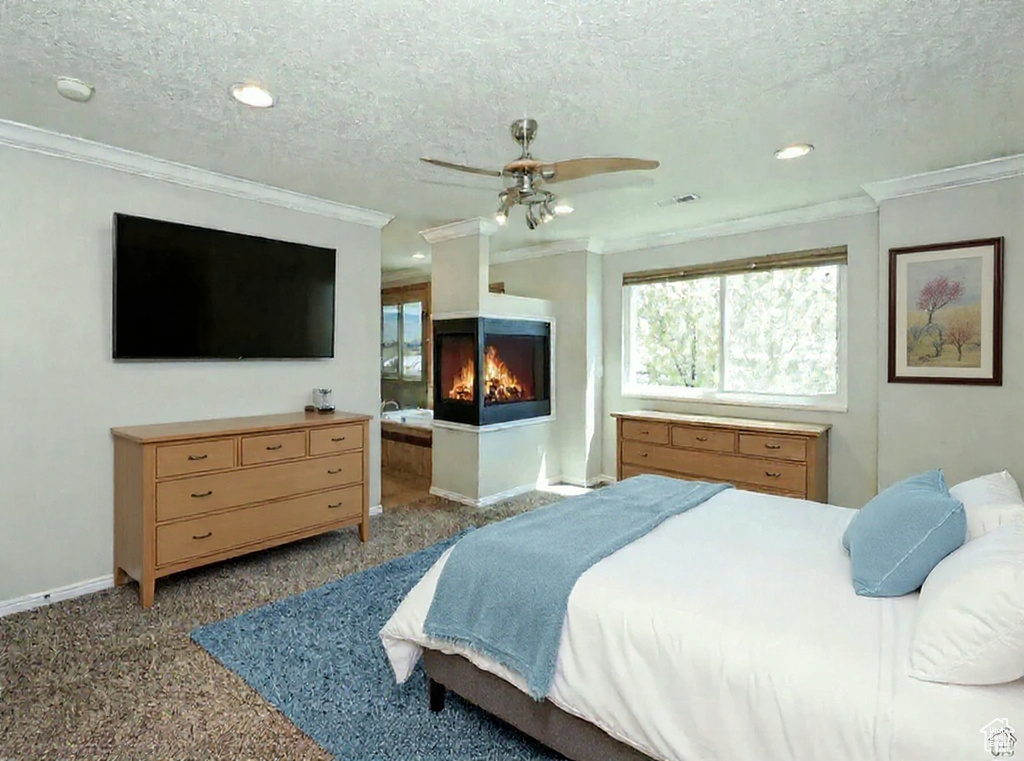 Carpeted bedroom with ornamental molding, a textured ceiling, a multi sided fireplace, recessed lighting, and ceiling fan