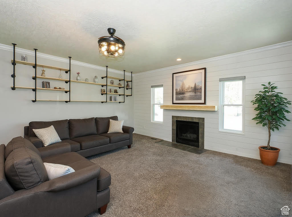 Living room with carpet, plenty of natural light, ornamental molding, a tile fireplace, and wooden walls