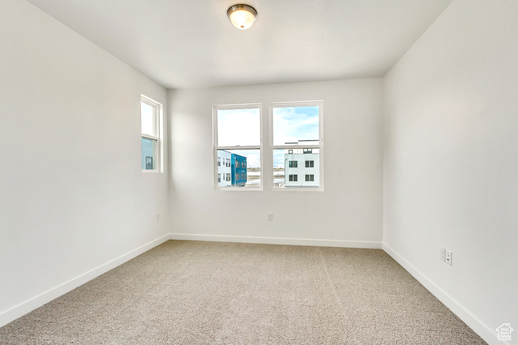 Spare room with baseboards and light colored carpet