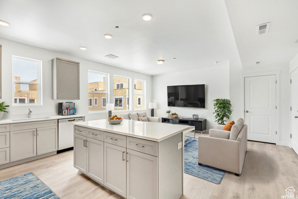 Kitchen with light countertops, dishwasher, visible vents, a kitchen island, and light wood-style flooring