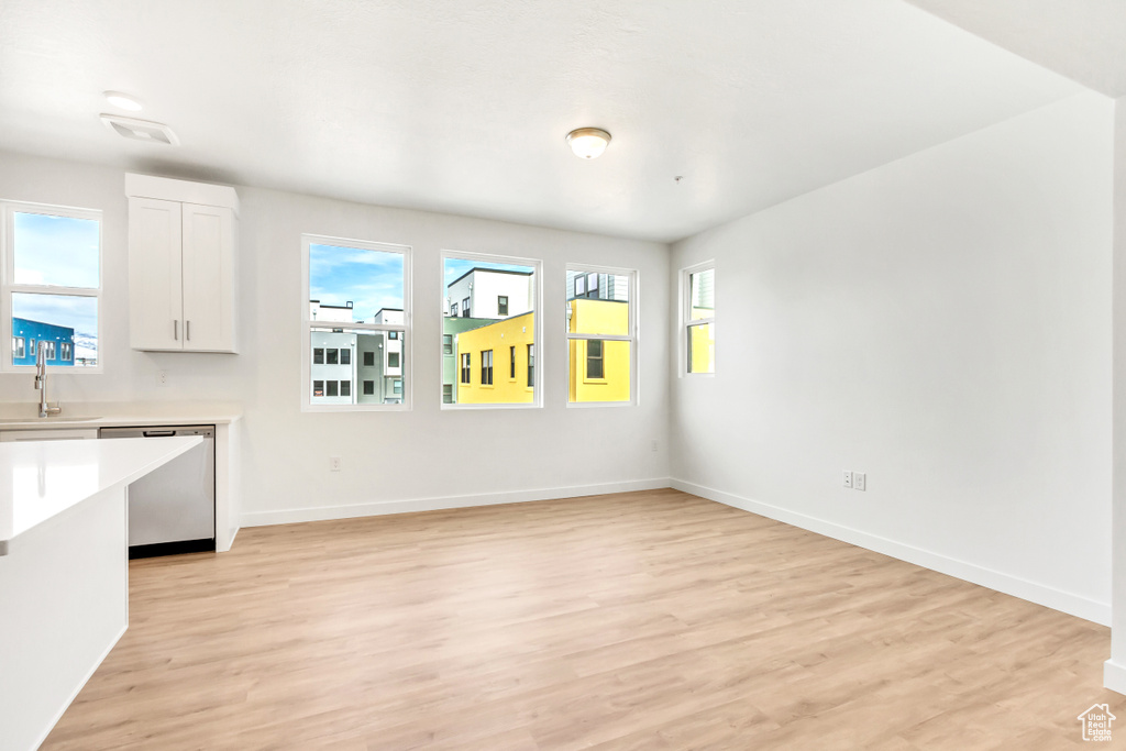 Unfurnished dining area featuring visible vents, light wood finished floors, baseboards, and a sink