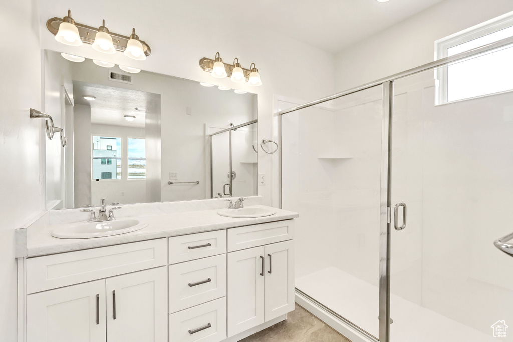 Bathroom featuring a healthy amount of sunlight, a sink, and a stall shower