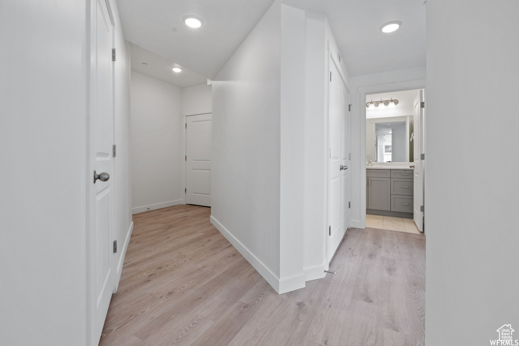 Hall with light wood-style flooring, baseboards, and recessed lighting