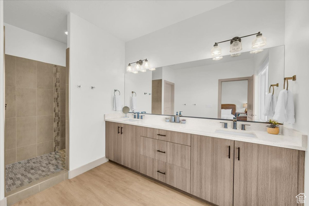 Ensuite bathroom with wood finished floors, a walk in shower, double vanity, and a sink