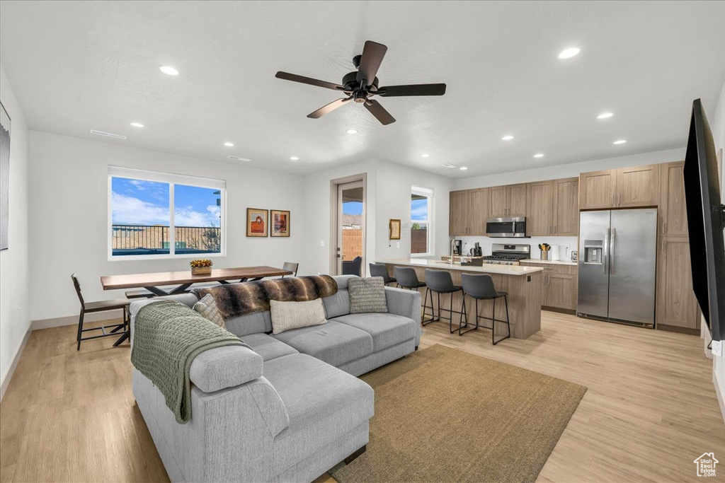 Living room with recessed lighting, ceiling fan, baseboards, and light wood-style floors