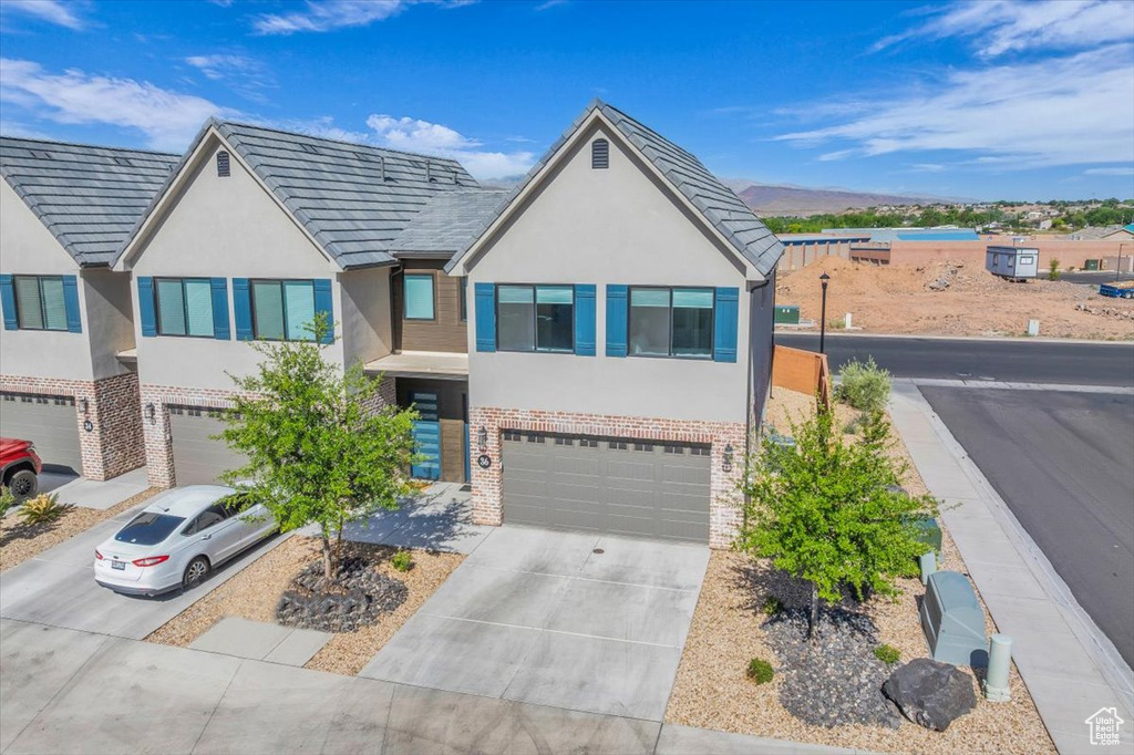 View of front of home featuring brick siding, stucco siding, concrete driveway, and an attached garage