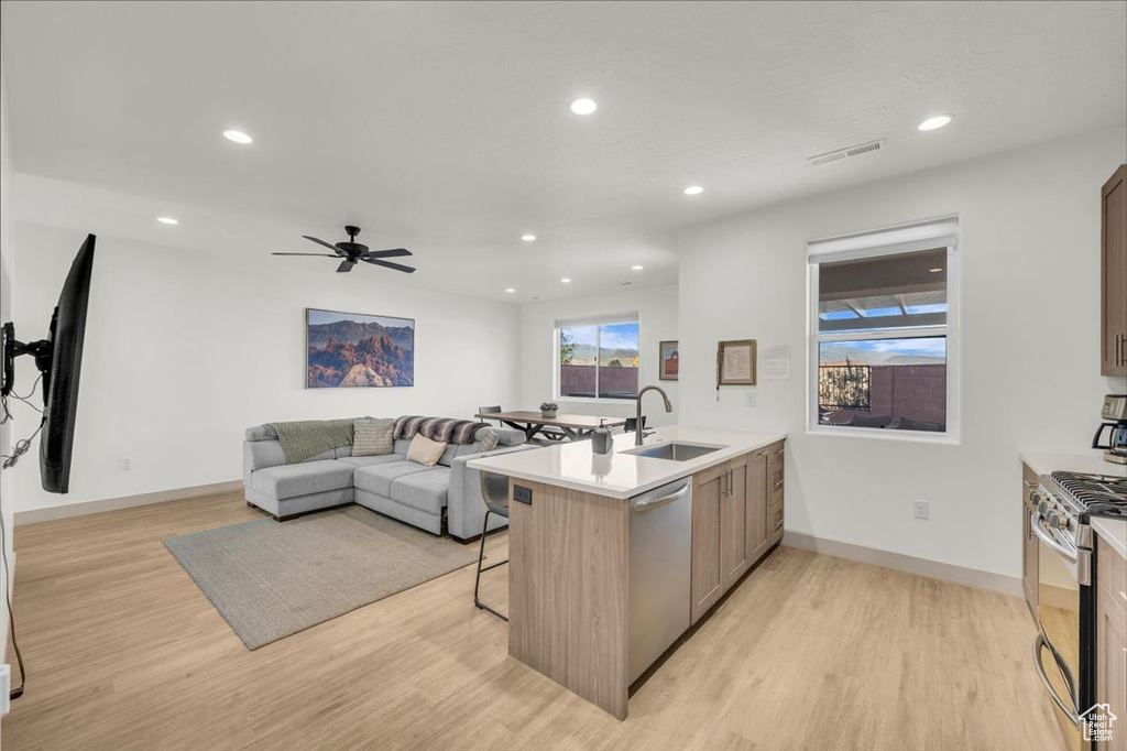 Kitchen with stainless steel appliances, light wood-style floors, a sink, visible vents, and a peninsula