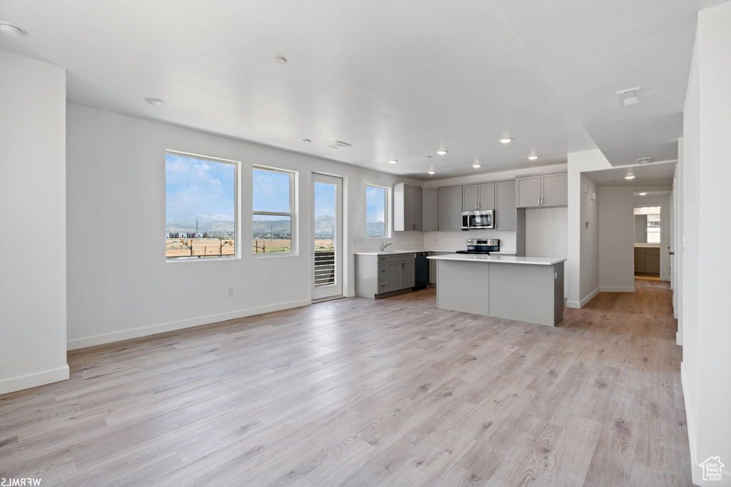 Kitchen featuring open floor plan, gray cabinets, baseboards, appliances with stainless steel finishes, and recessed lighting