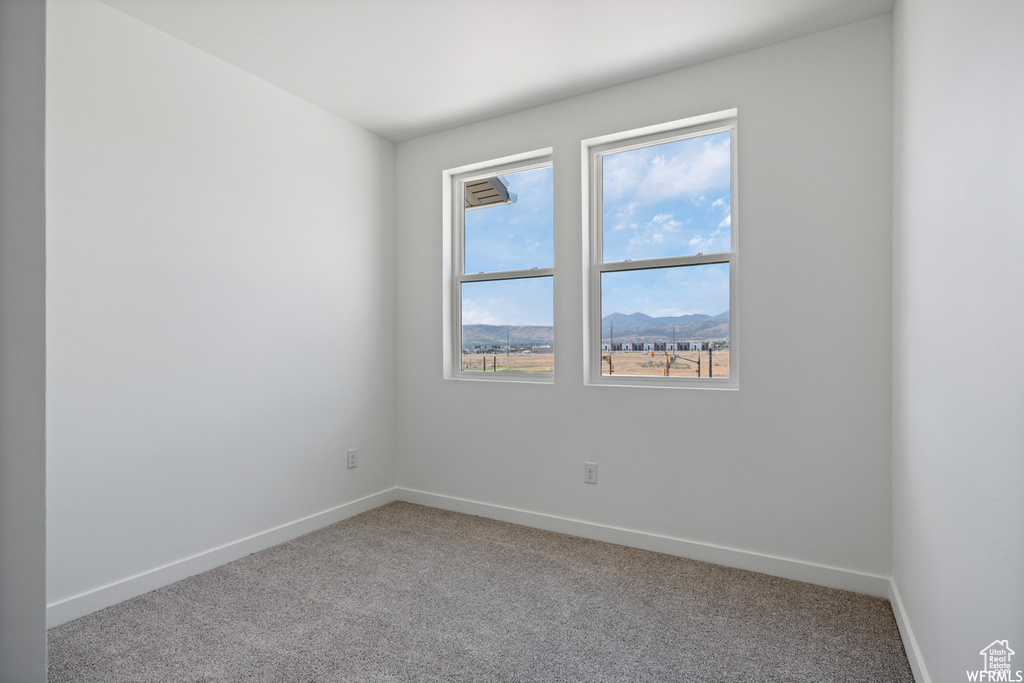 Carpeted empty room with baseboards and a mountain view