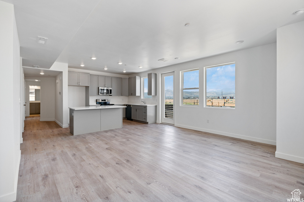 Kitchen with recessed lighting, light countertops, gray cabinets, baseboards, and appliances with stainless steel finishes