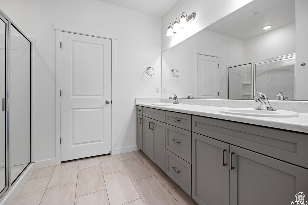 Bathroom with double vanity, a stall shower, and a sink