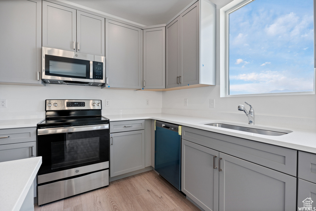 Kitchen with gray cabinetry, a sink, and appliances with stainless steel finishes