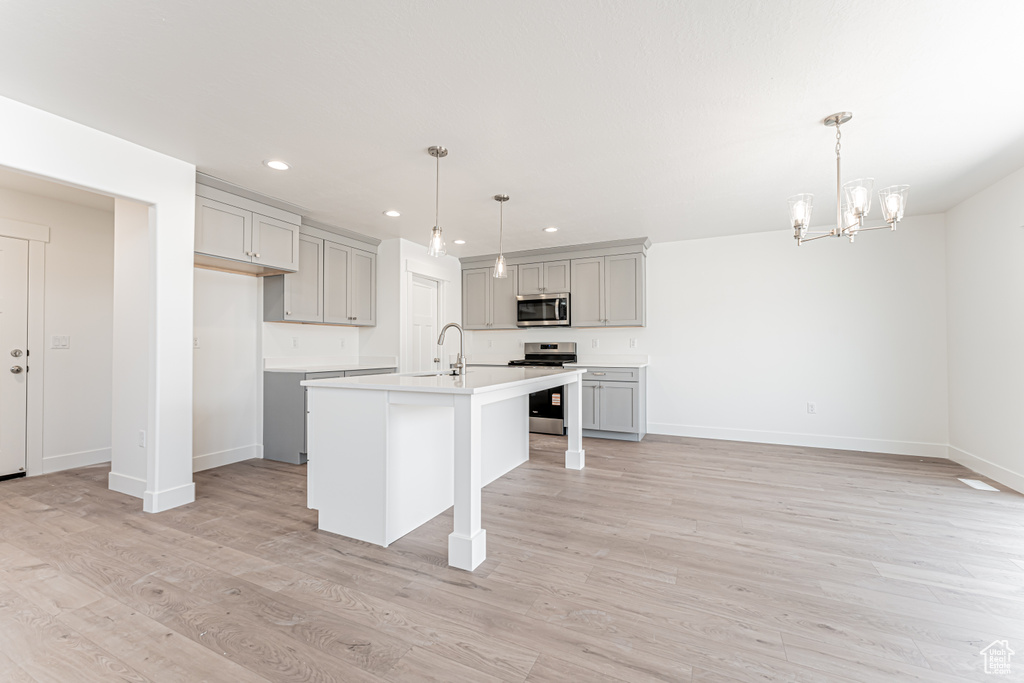 Kitchen featuring appliances with stainless steel finishes, gray cabinets, recessed lighting, a chandelier, and light countertops