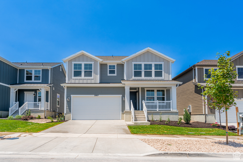 View of front of home with covered porch, board and batten siding, concrete driveway, and an attached garage