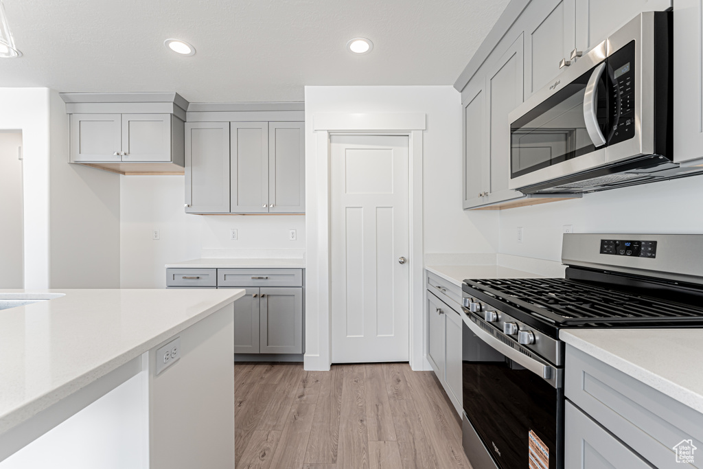 Kitchen featuring stainless steel appliances, light wood finished floors, light countertops, gray cabinetry, and recessed lighting