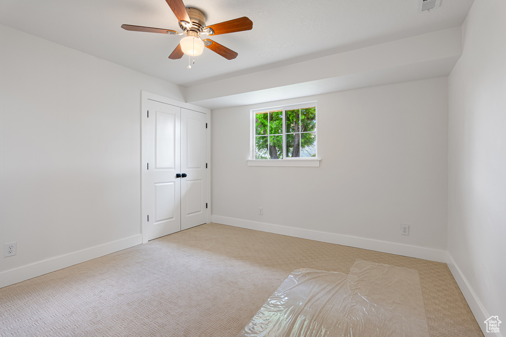 Unfurnished bedroom with light carpet, baseboards, ceiling fan, and a closet