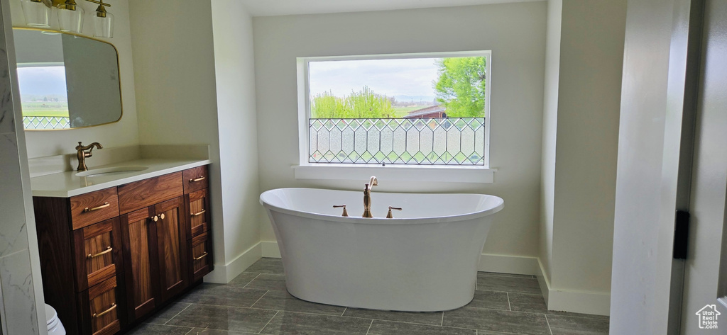 Bathroom featuring vanity, baseboards, and a soaking tub