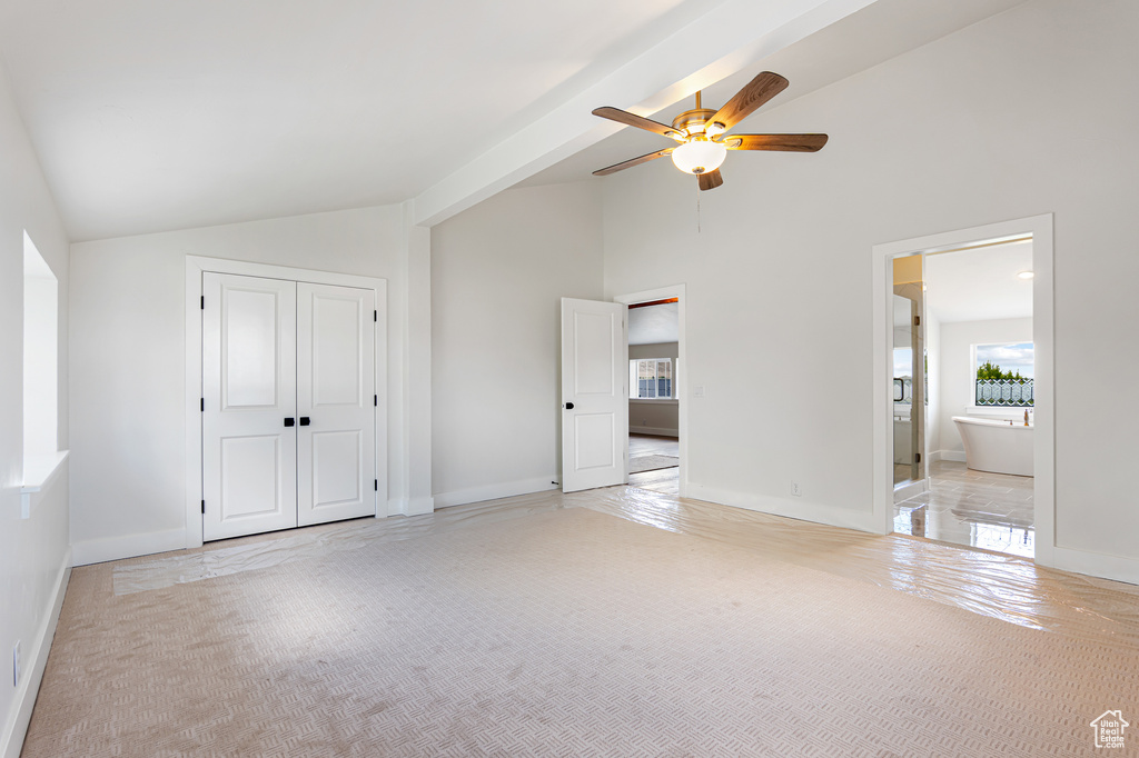 Unfurnished bedroom with light carpet, high vaulted ceiling, a closet, a ceiling fan, and ensuite bath