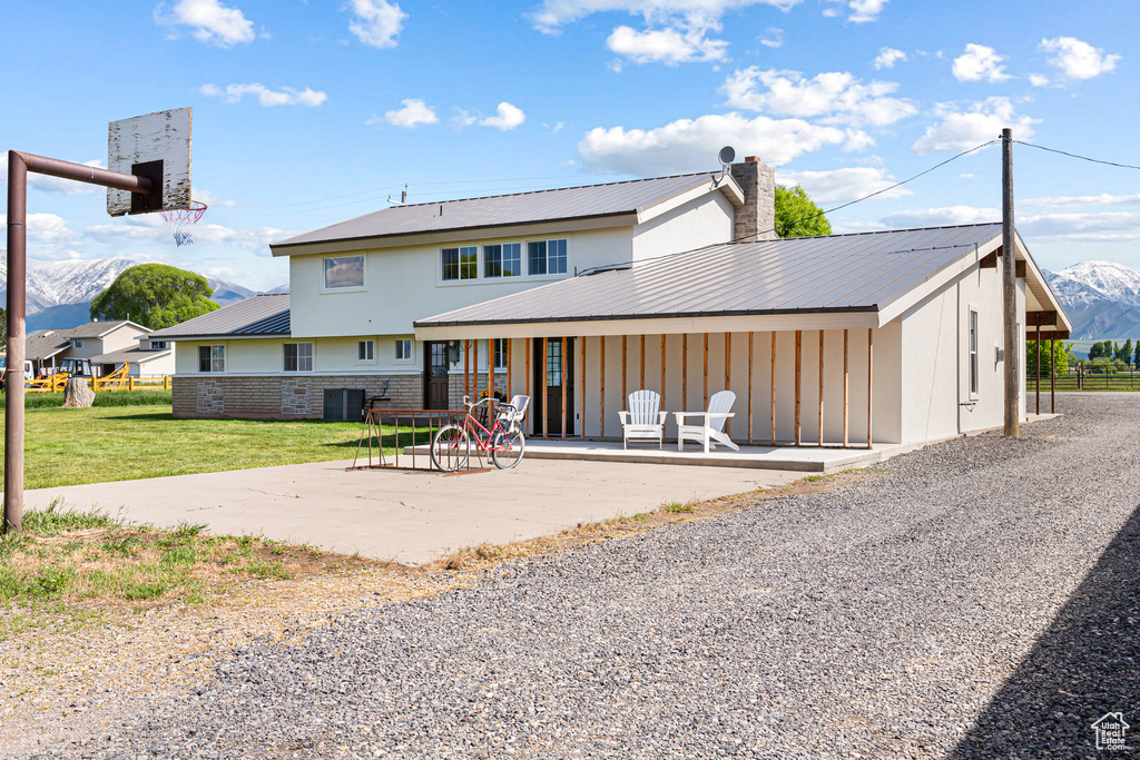 Rear view of property featuring a mountain view, metal roof, central air condition unit, a patio area, and a chimney