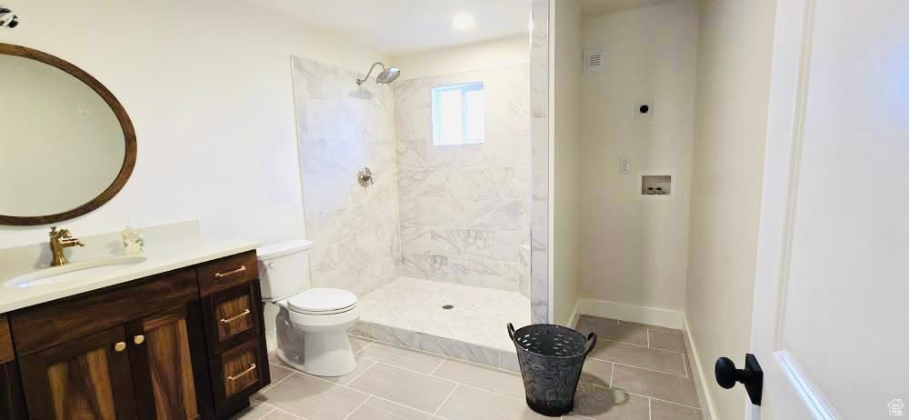 Full bath with vanity, tile patterned flooring, toilet, and tiled shower
