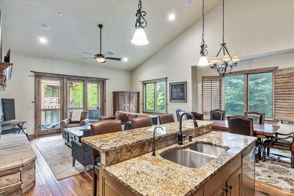 Kitchen with a sink, open floor plan, light wood-type flooring, a chandelier, and an island with sink