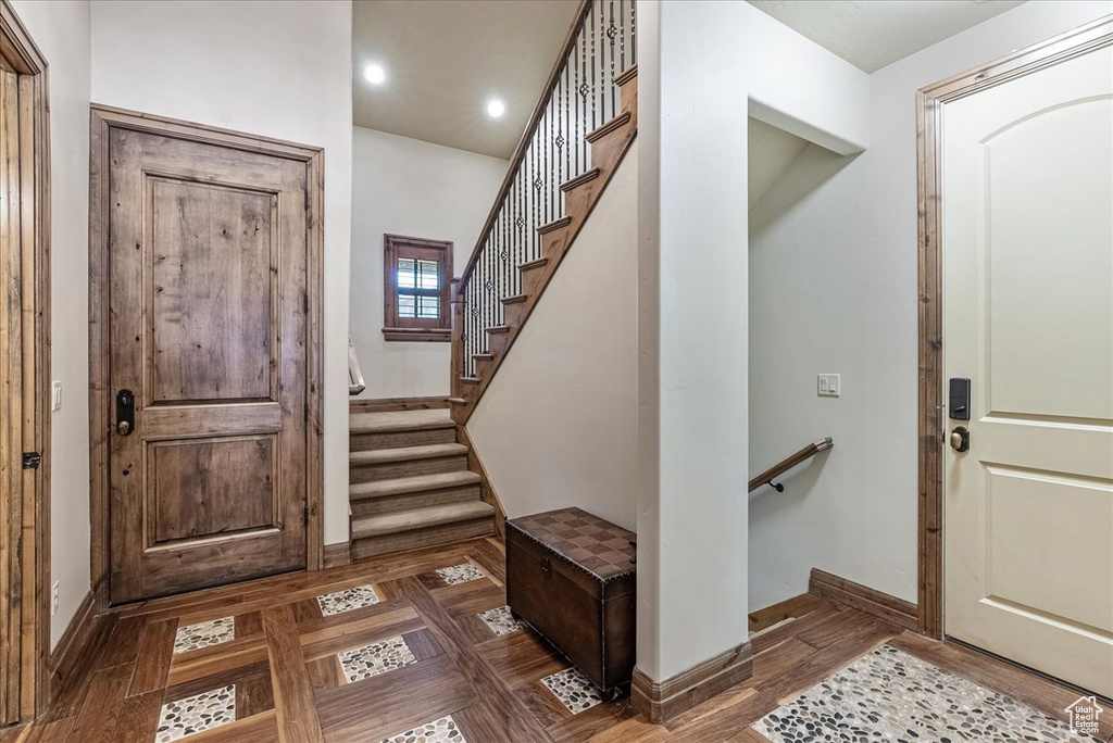 Foyer entrance with baseboards, recessed lighting, stairs, and parquet floors
